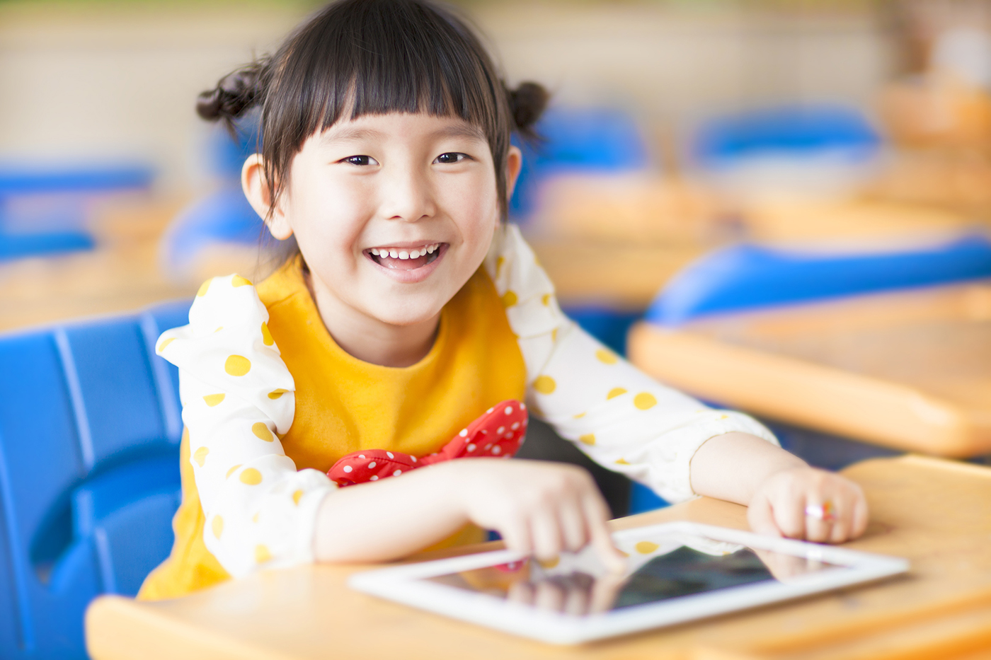 Happy girl on tablet - photo by iStock/Tomwang112