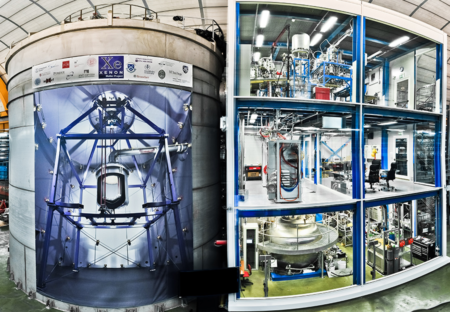 The XENON experiment located underground in the Italian LNGS laboratory. The detector is installed inside a large water shield; the building next to it accommodates its various auxiliary subsystems. Image courtesy of XENON1T collaboration