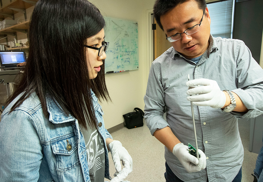 Postdoctoral Scholar Yuehuan Wei works with a student in the Ni Group to install a level meter in the liquid xenon detector development lab in Mayer Hall at UC San Diego.  Photo by Michelle Fredricks, UC San Diego Physical Sciences