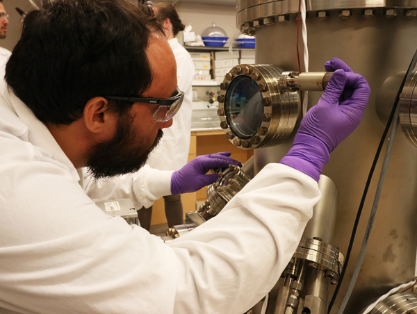 Nicolas Vargas, postdoctoral researcher at UC San Diego, uses a second Organic Molecular Beam Epitaxy (OMBE) to evaporate and grow low dimensional magnetic chains. Graduate student Jamie Wampler and postdoctoral researcher Alex Hojem are pictured in the background. Photo by Michelle Fredricks