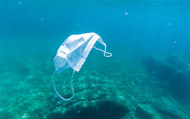 A discarded face mask floats in the ocean.