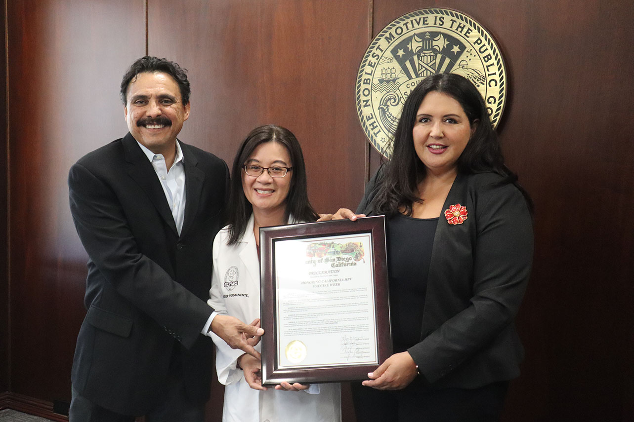 Jesse Nodora of University of California San Diego, Dr. Vi Nguyen, chair of the American Academy of Pediatrics-CA3 Chapter Advisory Committee and Kaiser Permanente physician, and Nora Vargas, County of San Diego Board of Supervisors, hold a County of San Diego HPV Awareness Week proclamation.