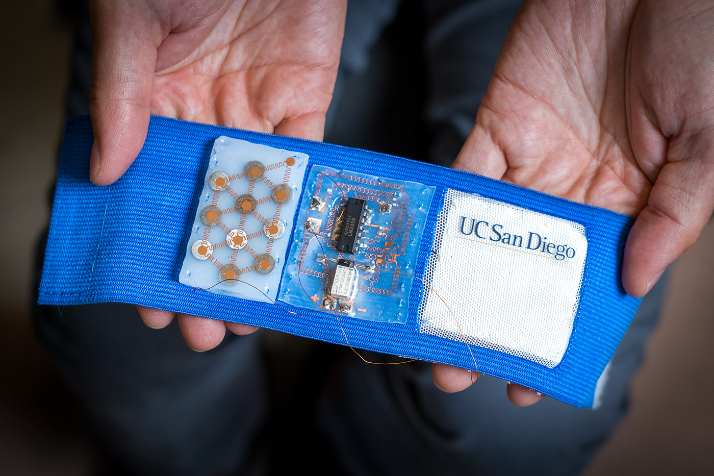 Armband embedded with flexible battery pack (left), stretchable circuit (center), and cooling/heating patch (right). Credit: UCSD.edu
