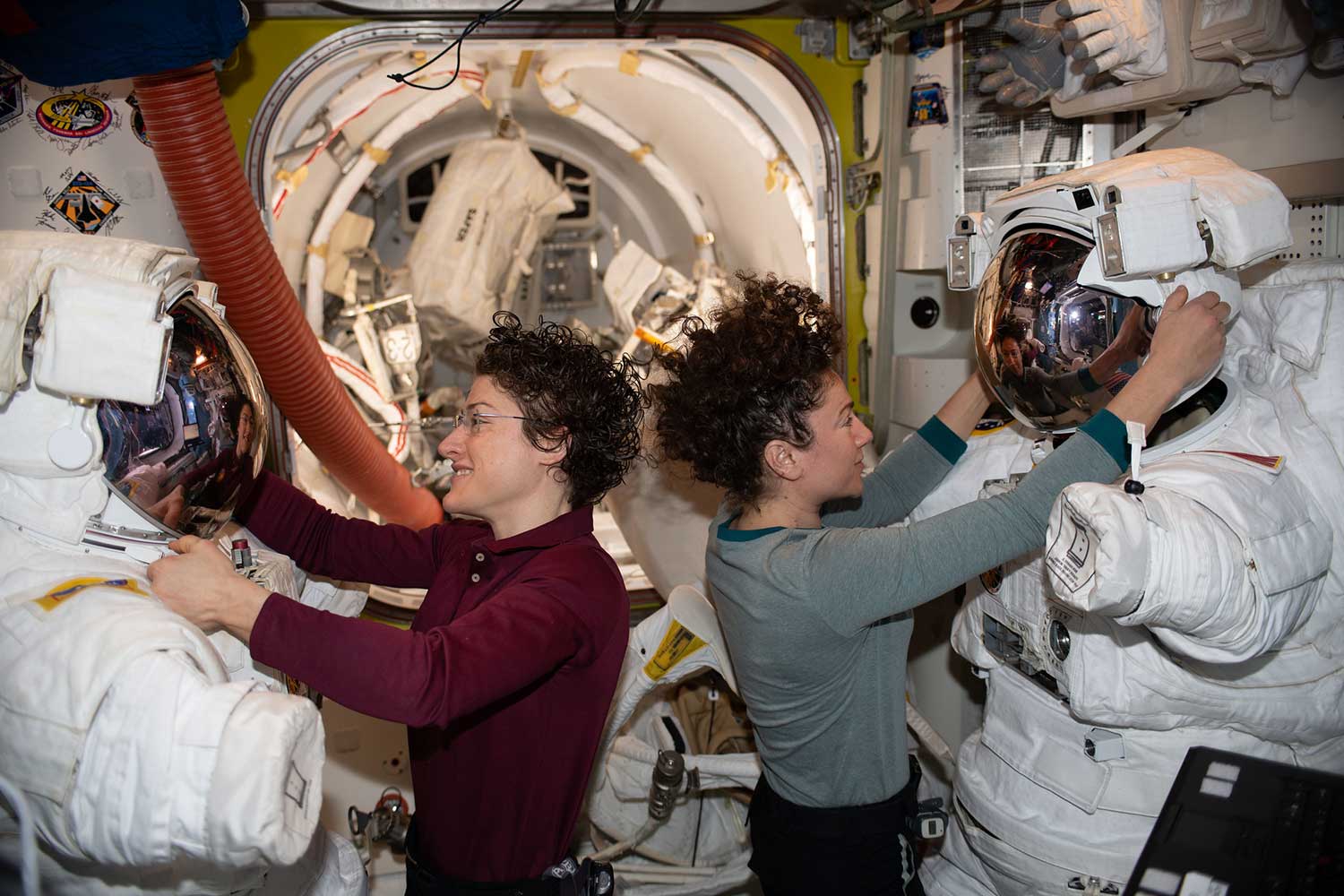 NASA astronauts Christina Koch and Jessica Meir work on their U.S. spacesuits.