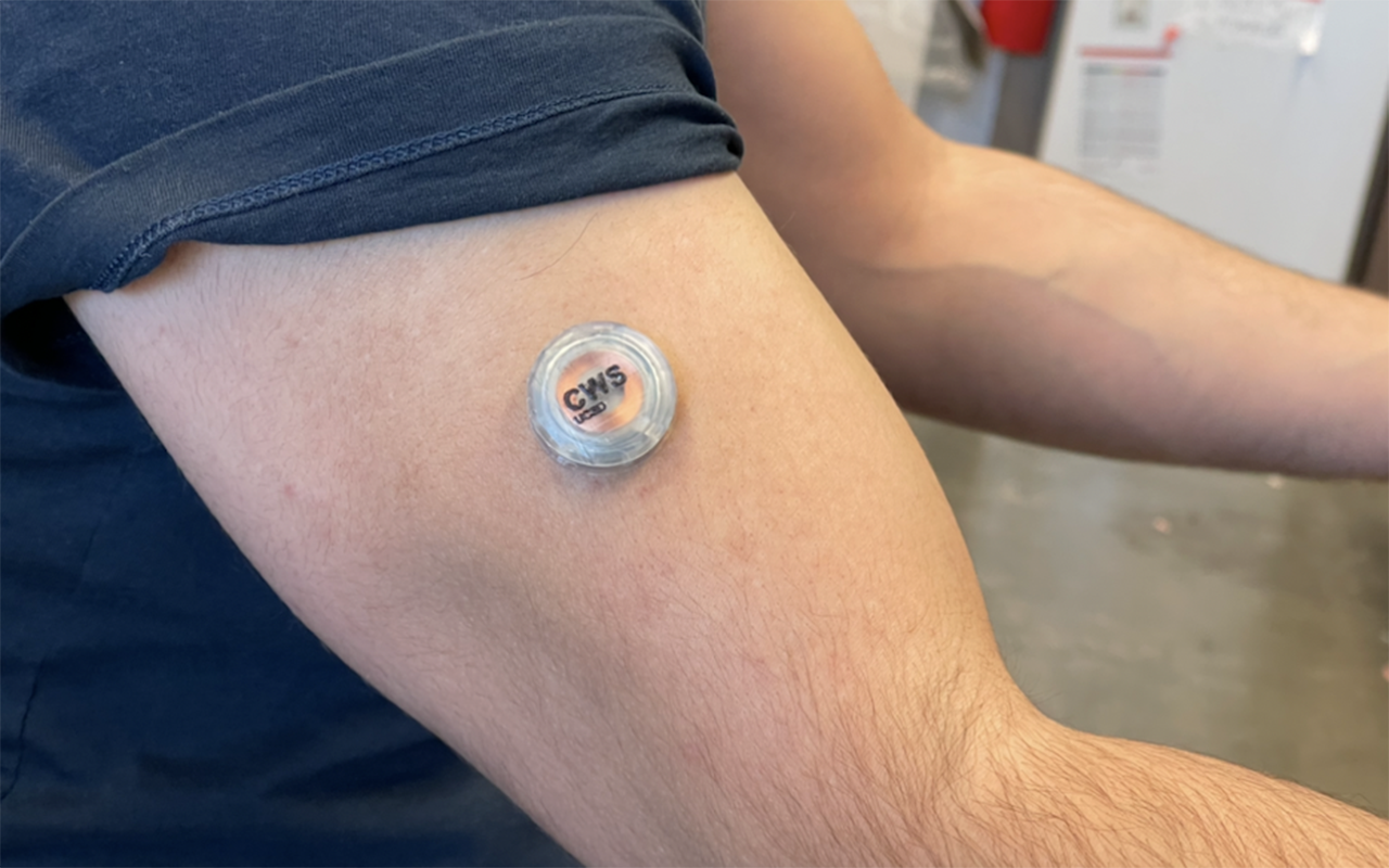 Button-like electronic device worn on a person's upper arm.